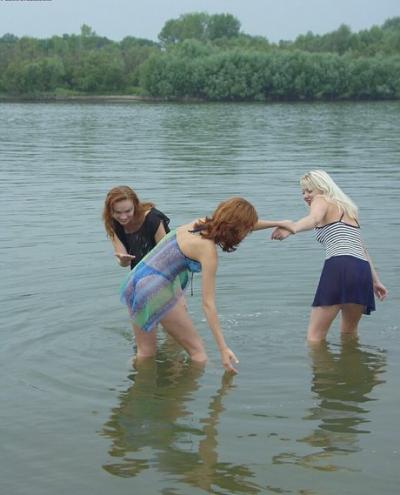 Teen girls partially remove wet clothing after wading into a river